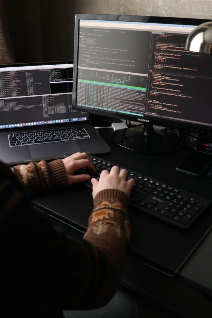 a person sitting at a desk with a laptop and a computer monitor